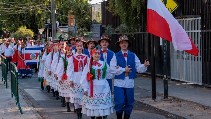 tancerze w strojach krośnieńskich niosący flagę Polski